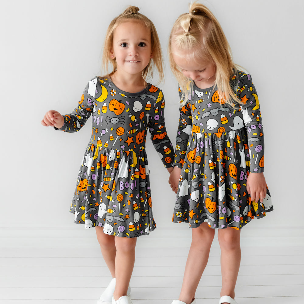 Two children holding hands wearing Hey Boo printed twirl dresses with bodysuits