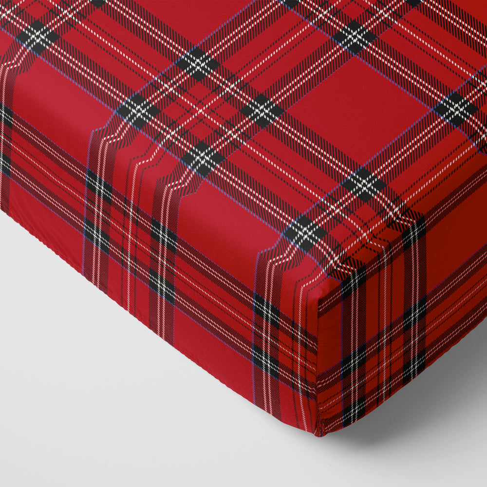 Corner of a mattress with a Holiday Plaid fitted crib sheet on