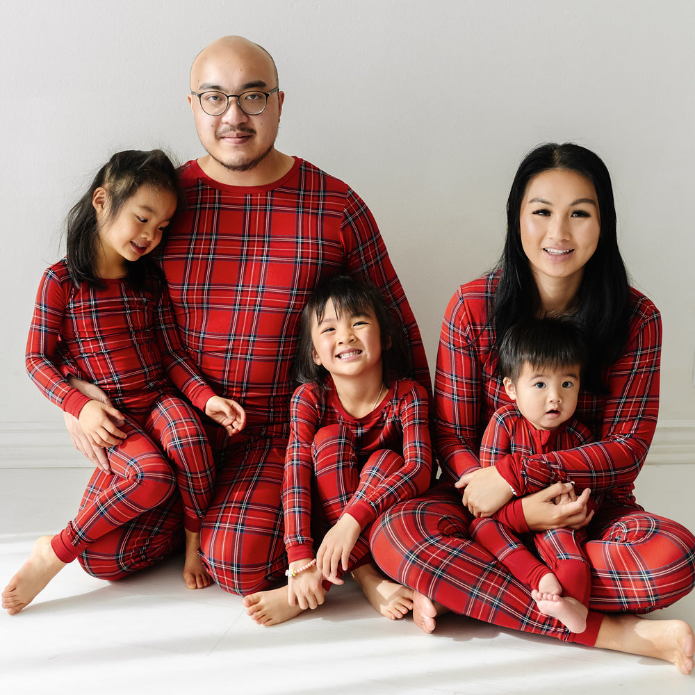 Family of five wearing matching Holiday Plaid pajamas in men's, women's, and children's two piece styles