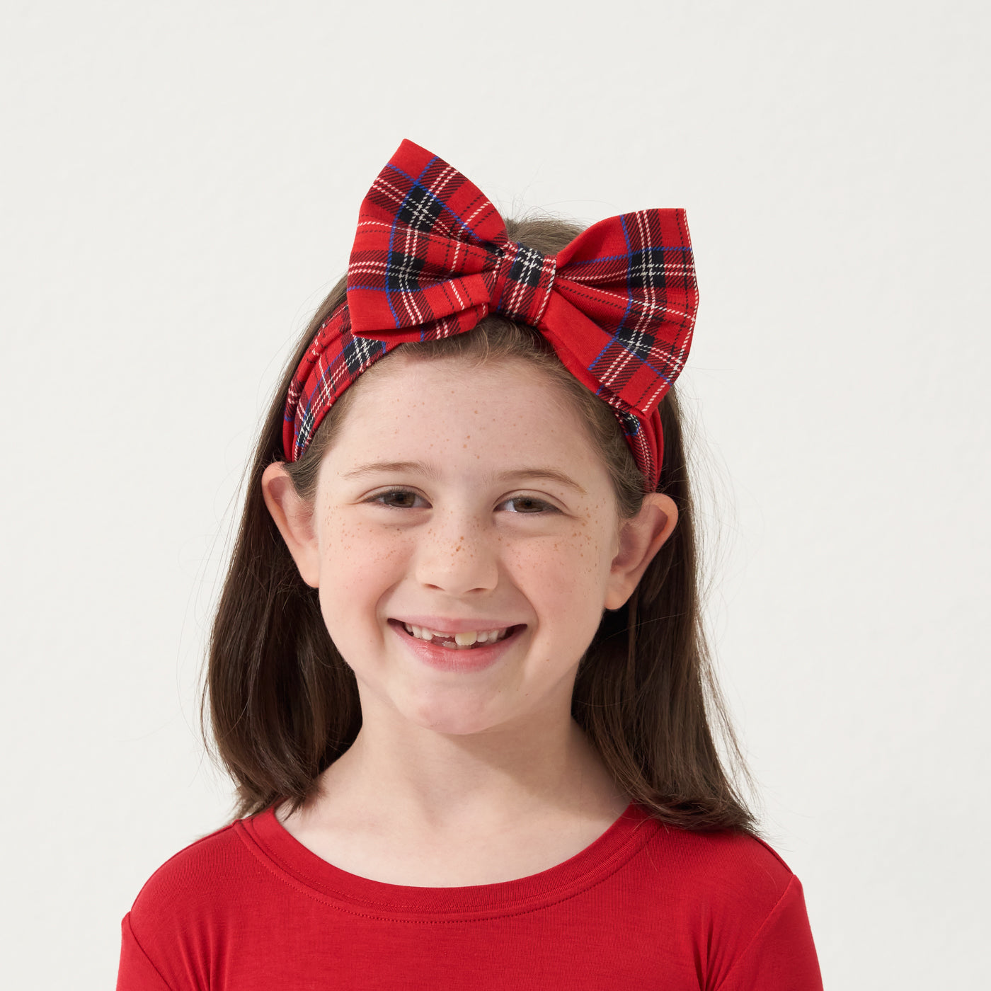 Close up image of a child wearing a Holiday Plaid luxe bow headband