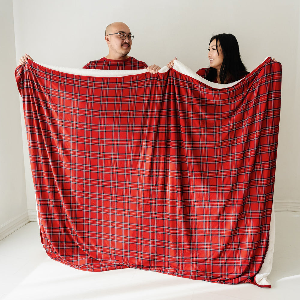 Man and woman holding up a Holiday Plaid oversized cloud blanket