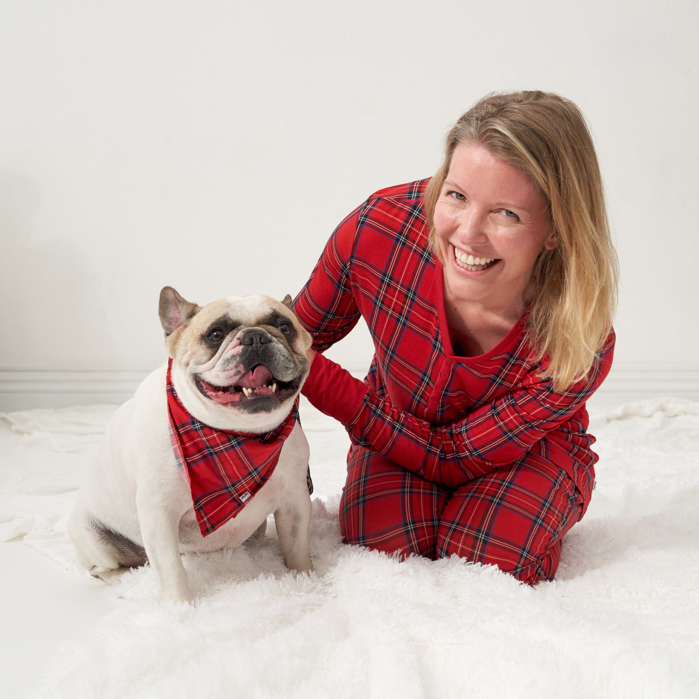 Dog and woman sitting on the ground wearing a Holiday Plaid pet bandana and matching adult pajamas