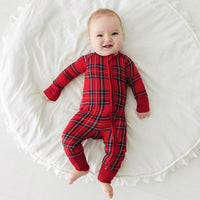 Child laying on a bed wearing a Holiday Plaid zippy