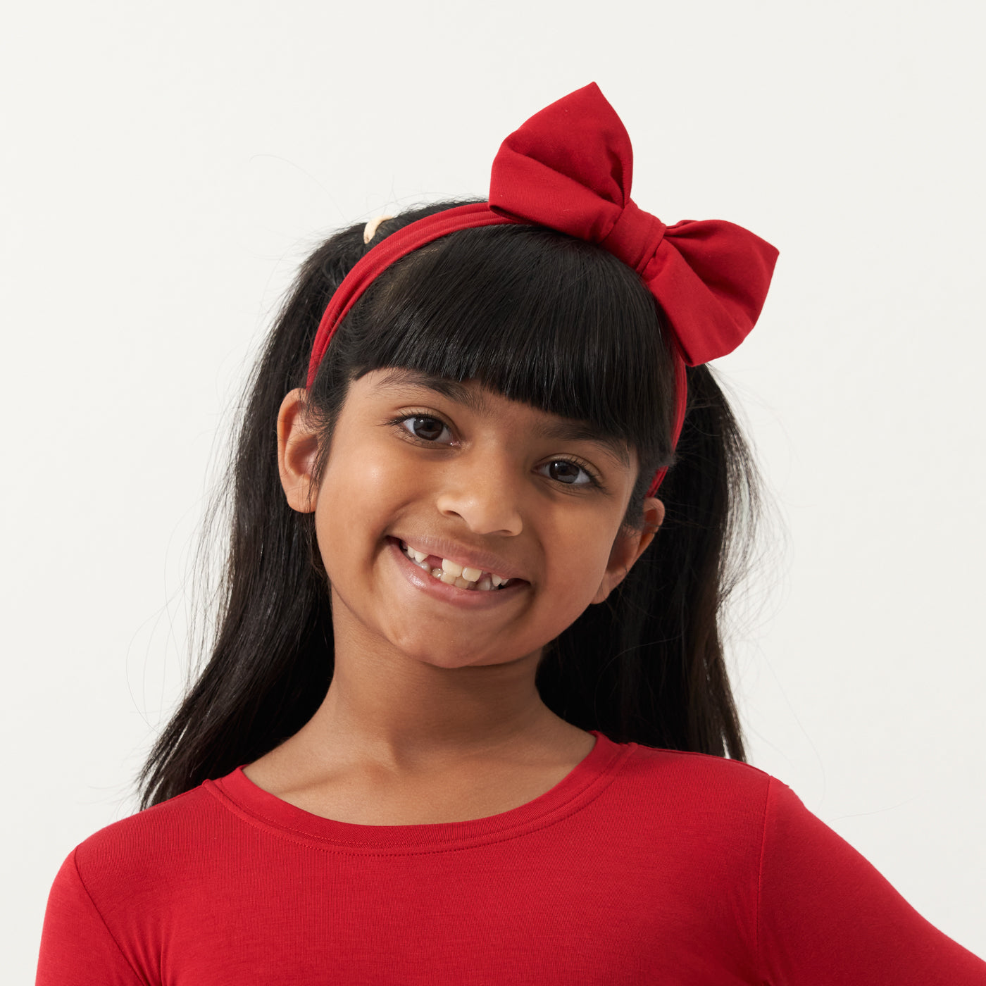 Child wearing a Holiday Red luxe bow headband and matching pajamas