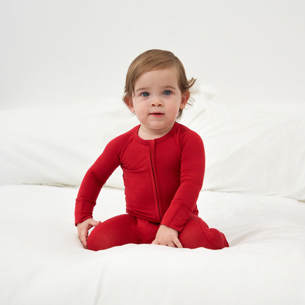 Child sitting on a bed wearing a Holiday Red zippy