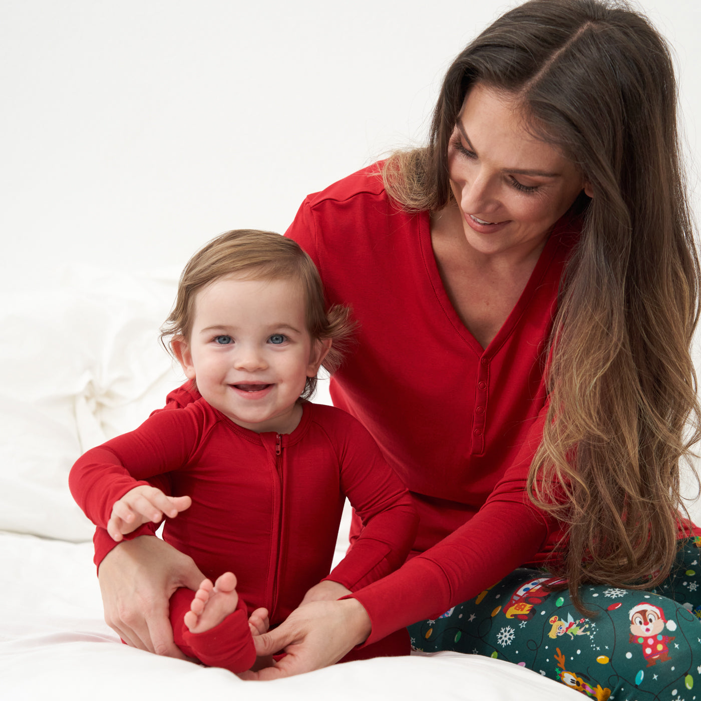 Mother and child sitting on a bed wearing matching Holiday pajamas