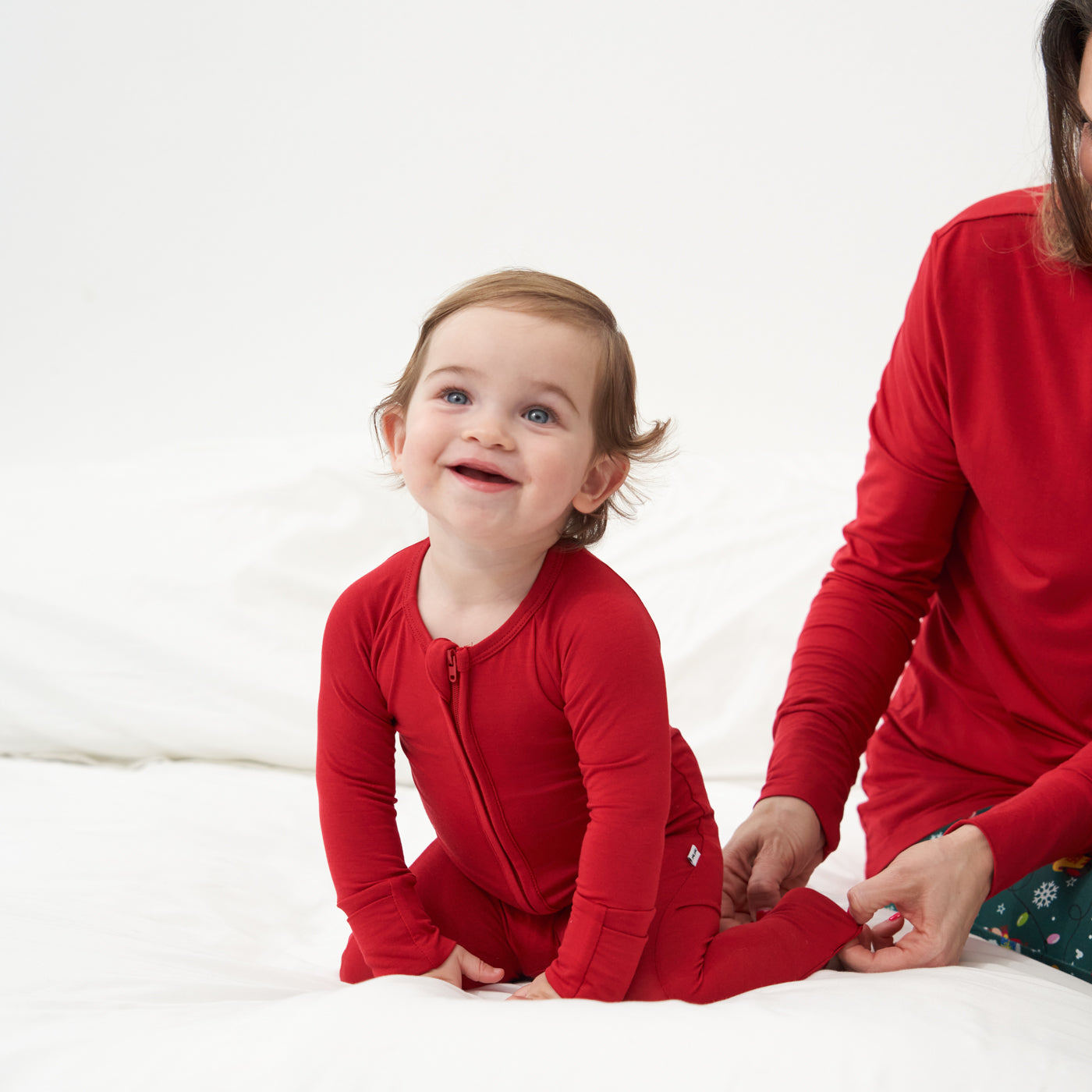 Alternate image of a mother and child sitting on a bed wearing matching holiday pajamas