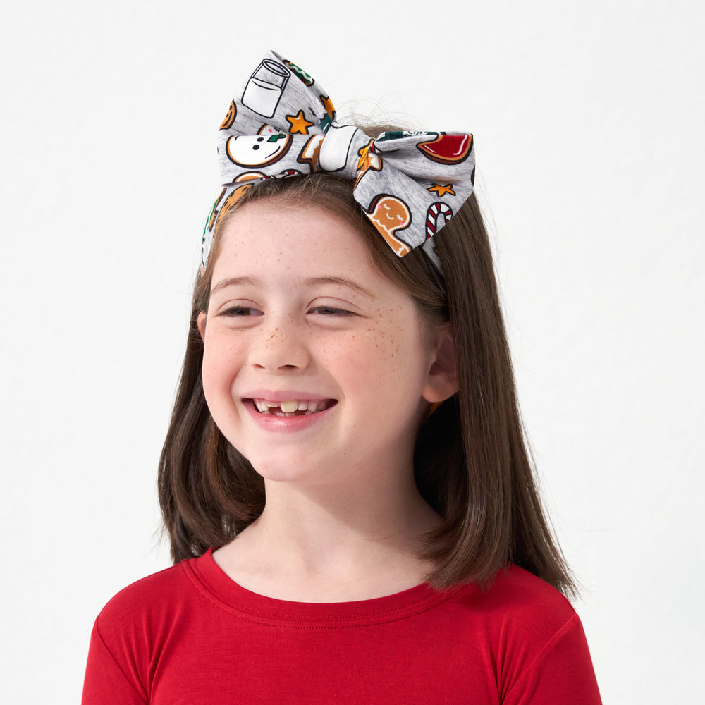 Profile view of a child wearing a Holiday Treats luxe bow headband paired with a Holiday Red two piece pajama set