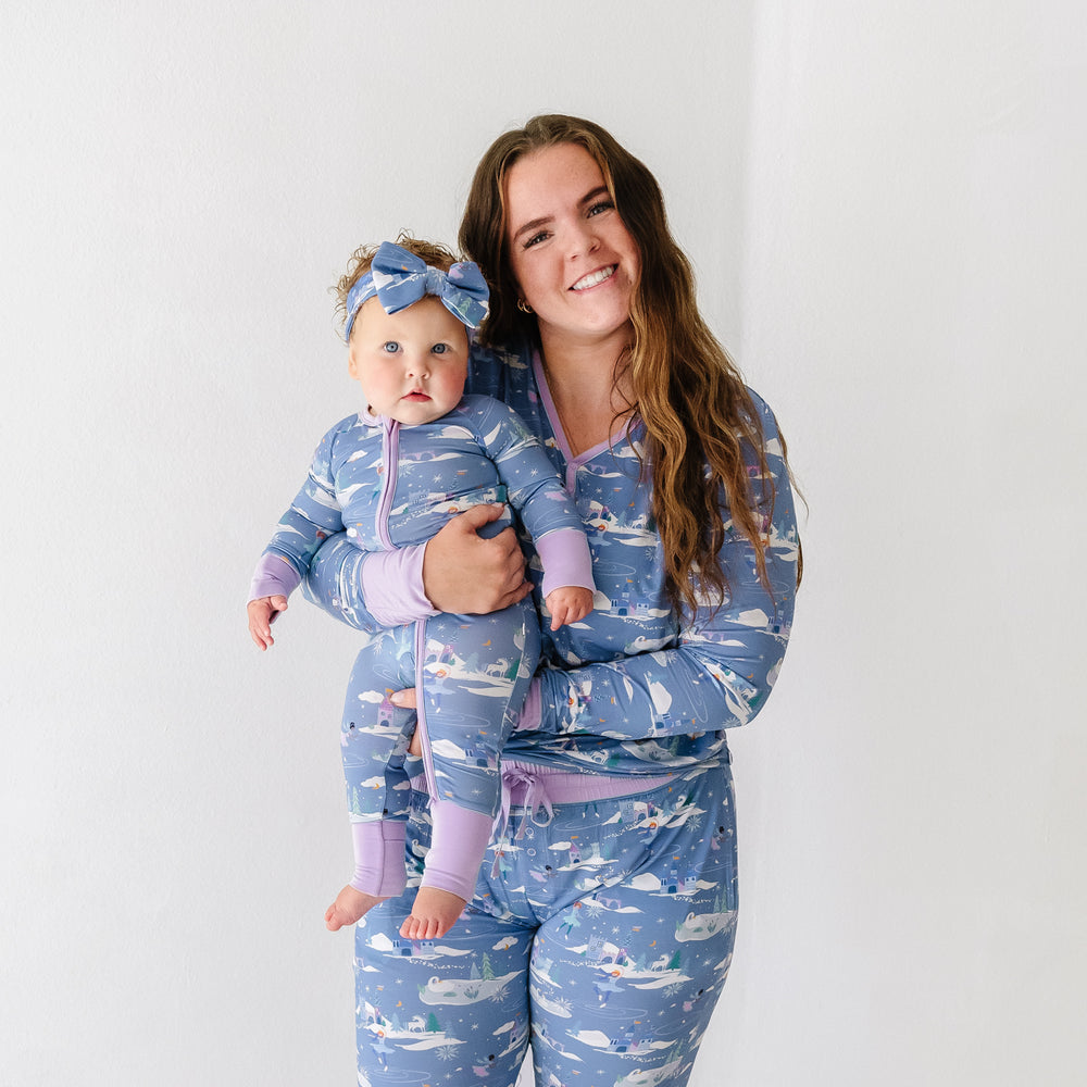 Mother and daughter matching wearing Ice Princess printed pajamas. Mom is wearing women's Ice Princess women's pajama top paired with matching women's pajama pants. Her daughter is wearing an Ice Princess zippy paired with a matching luxe bow headband