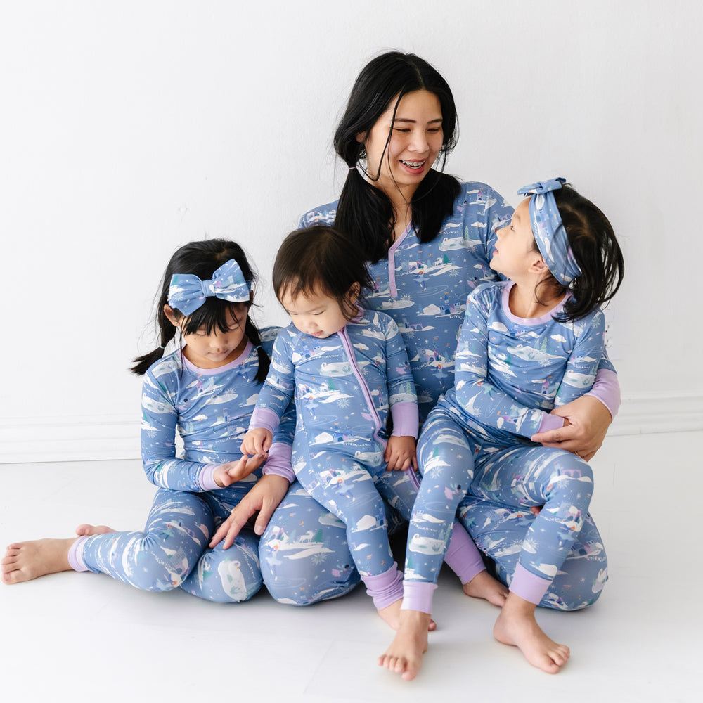 Mother and three daughters matching wearing Ice Princess printed pajamas. Mom is wearing women's Ice Princess women's pajama top paired with matching women's pajama pants. Her daughters are wearing Ice Princess pajamas in zippy and two piece styles paired with a matching luxe bow headband