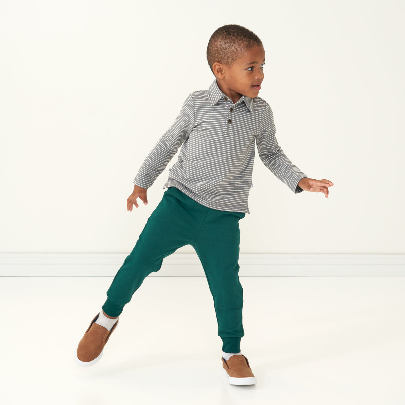Child posing wearing Emerald Joggers paired with a Heather Gray Stripe polo shirt