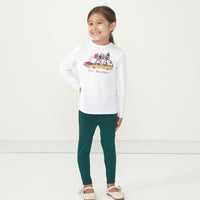 Alternate image of a child posing wearing Emerald leggings paired with a Happy Howlidays graphic tee
