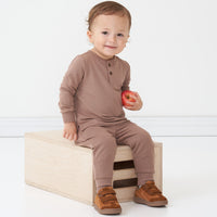Child sitting on a box wearing a Light Cocoa henley tee and matching joggers