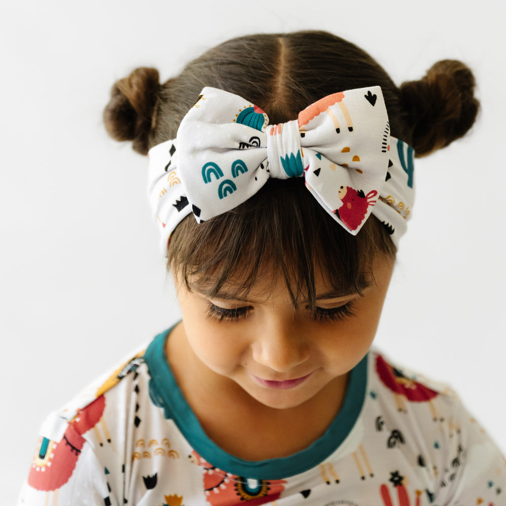 Child wearing a Llama Love luxe bow headband and matching pajamas
