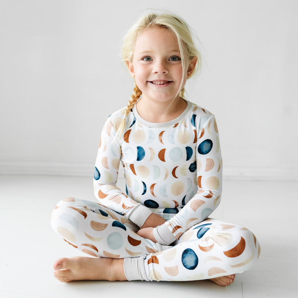 Child sitting on the floor wearing a Luna Neutral two piece pj set