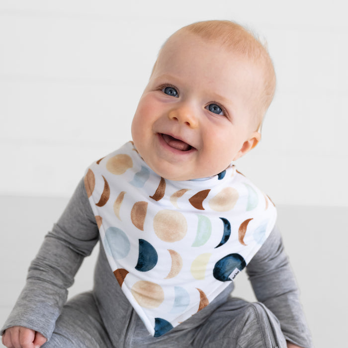 Close up of a child wearing a Luna Neutral Bandana Bib over Heather Gray bamboo pajamas