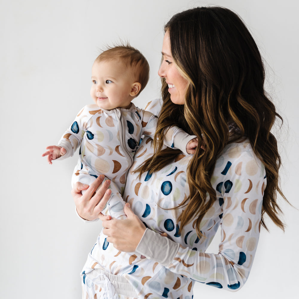 Image of a mother and son in matching Luna Neutral long sleeve pajamas. This print features phases of the moon in the sweetest shades of creams, tans, and navy watercolor in an all over repeat pattern.