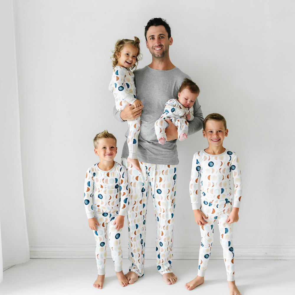 Dad and his four children wearing matching Luna Neutral pjs. Dad is wearing Heather Gray men's long sleeve pj top paired with Luna Neutral pj pants. Children are wearing Luna Neutral pjs in two piece and zippy styles