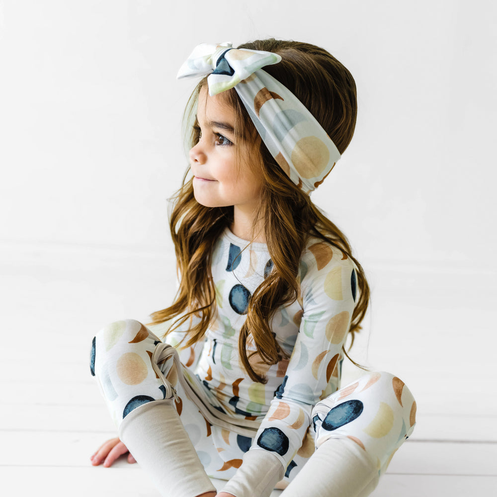 Child wearing a Luna Neutral crescent zippy paired with a matching luxe bow headband
