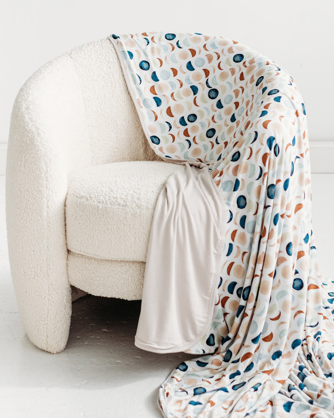 Luna Neutral oversized bamboo blanket draped over the side of a white chair.