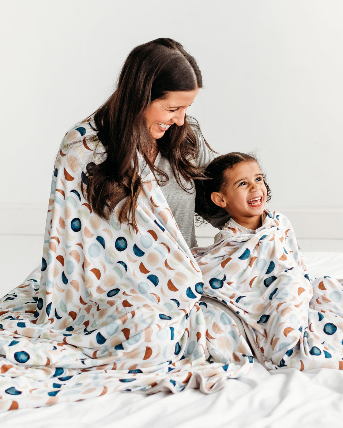 Mother and daughter cuddling under a Luna Neutral oversized bamboo blanket 