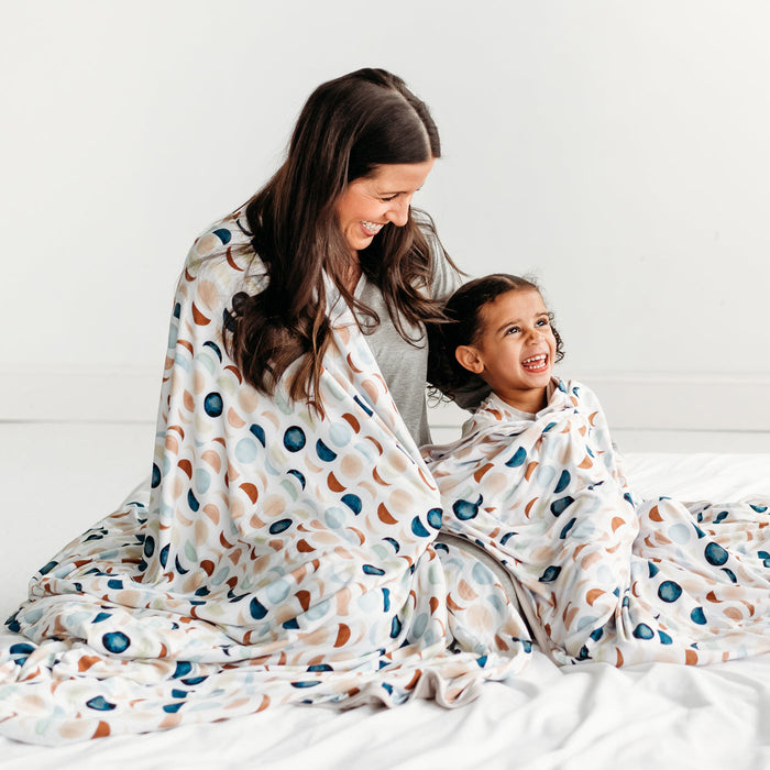 Mother and daughter cuddling under a Luna Neutral oversized bamboo blanket 