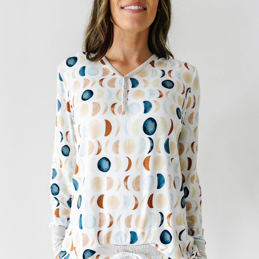 Click to see full screen - Cropped image of a woman wearing Luna Neutral printed pajama top and pajama pants. This print features phases of the moon in the sweetest shades of creams, tans, and navy watercolor in an all over repeat pattern.