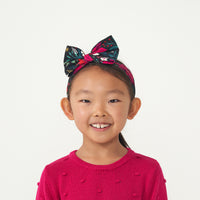 Child wearing a Berry Merry luxe bow headband paired with a Mixed Berry Pom Pom sweater