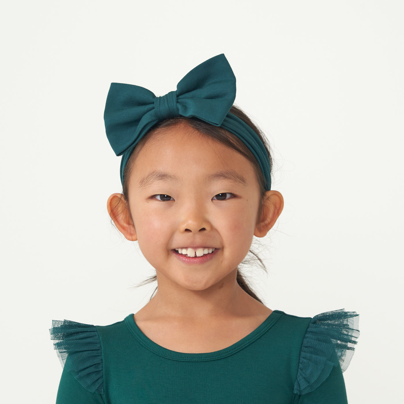Child wearing an Emerald flutter tutu dress paired with an Emerald luxe bow headband