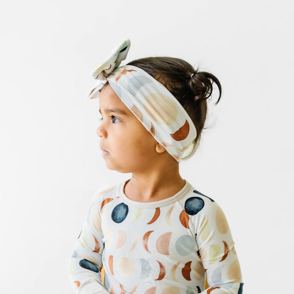 Profile image of a child waring a Luna Neutral luxe bow headband with a matching two piece pajama set