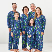 Family of six posing together wearing matching Blue Merry and Bright pajamas. Dad and Grandpa are wearing men's Blue Merry and Bright pajama bottoms paired with matching Blue Merry and Bright pajama tops. Mom and Grandma are wearing women's Blue Merry and Bright pajama bottoms and matching women's Blue Merry and Bright pajama tops. Their kids are wearing Blue Merry and Bright two piece pajama sets