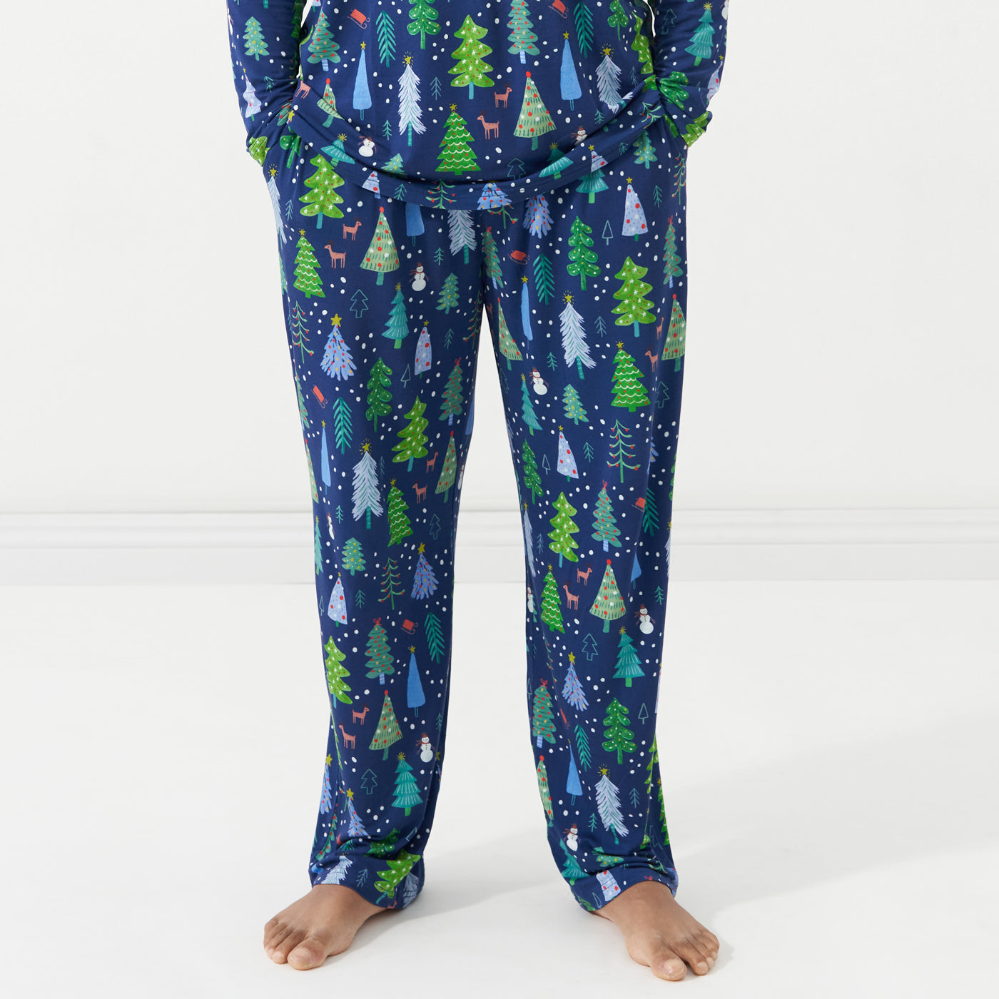 Close up image of man posing with his hands in his pockets wearing Blue Merry and Bright printed pajama bottoms