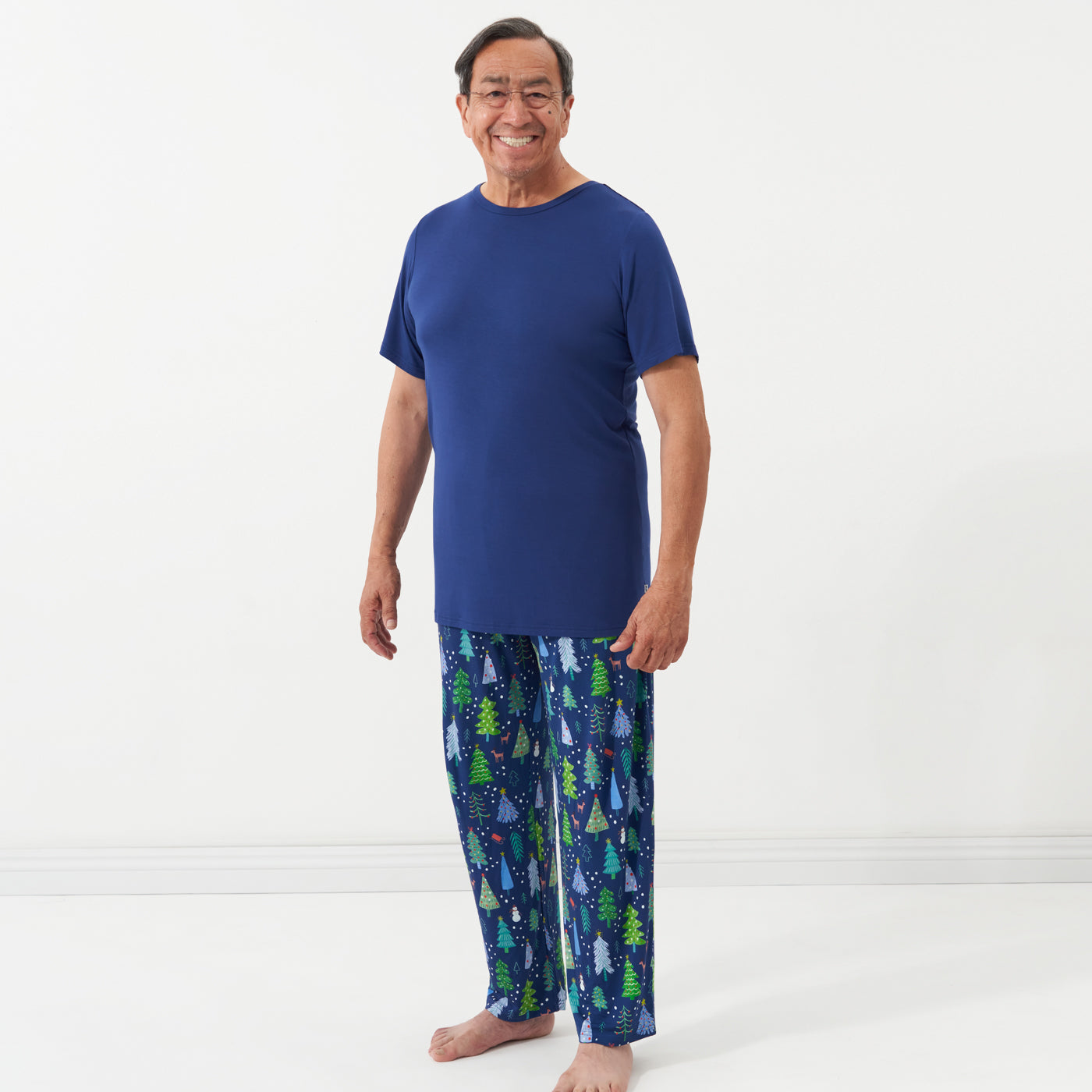 Man is wearing men's Blue Merry and Bright pajama bottoms paired with a solid Sapphire short sleeve pajama top.