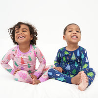 Two children sitting together wearing coordinating Pink and Blue Merry and Bright two piece pajama sets