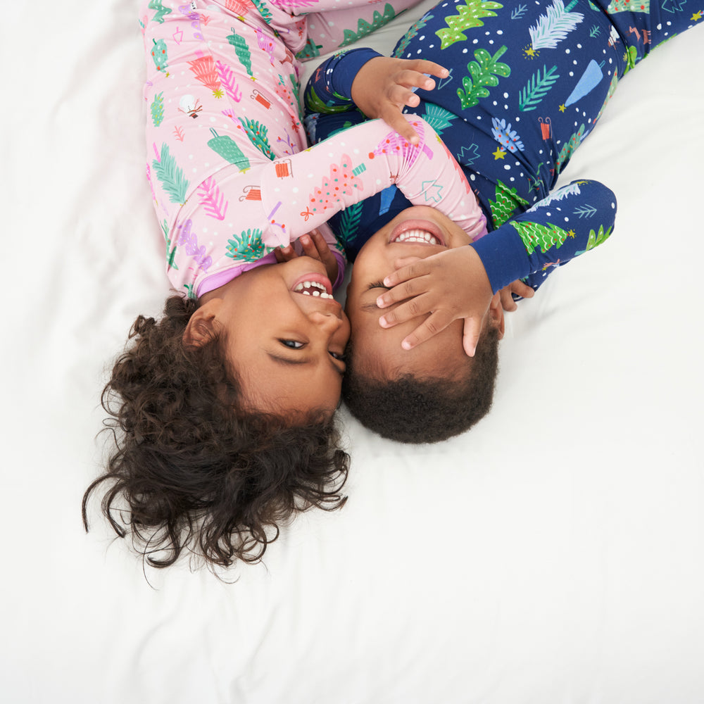 Two children cuddling together wearing coordinating Pink and Blue Merry and Bright two piece pajama sets