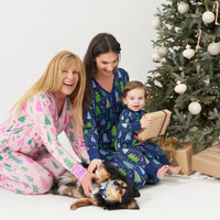 Grandmother, Mom, and Child together in coordinating Merry and Bright pajamas. Grandma is wearing women's Pink Merry and Bright women's pajama top paired with matching women's pajama pants. Mom is wearing Blue Merry and Bright women's pajama top paired with matching women's pajama pants. Child is wearing a Blue Merry and Bright zippy and their dog is wearing a matching pet bandana. 