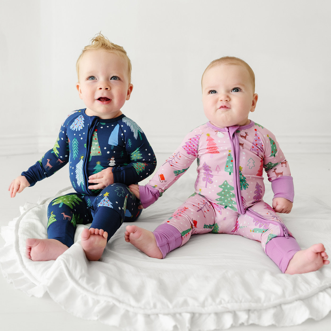 two children sitting together wearing matching Pink and Blue Merry and Bright zippies