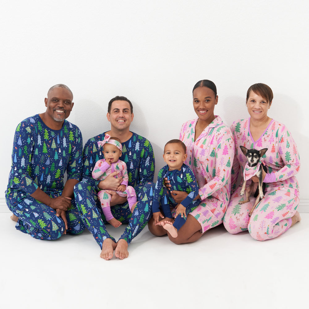 family of six wearing matching Merry and Bright pajamas. Dad and Grandpa are wearing Blue Merry and Bright printed men's pajama top and men's pajama bottoms. Grandma is wearing Pink Merry and Bright women's pajama top and pajama bottoms. Mom is wearing a Pink Merry and Bright women's sleep shirt. Children are wearing Blue and Pink Merry and Bright zippies. Their daughter is pairing her Pink Merry and Bright zippy with a matching luxe bow headband and their dog is wearing a Pink Merry and Bright pet bandana.