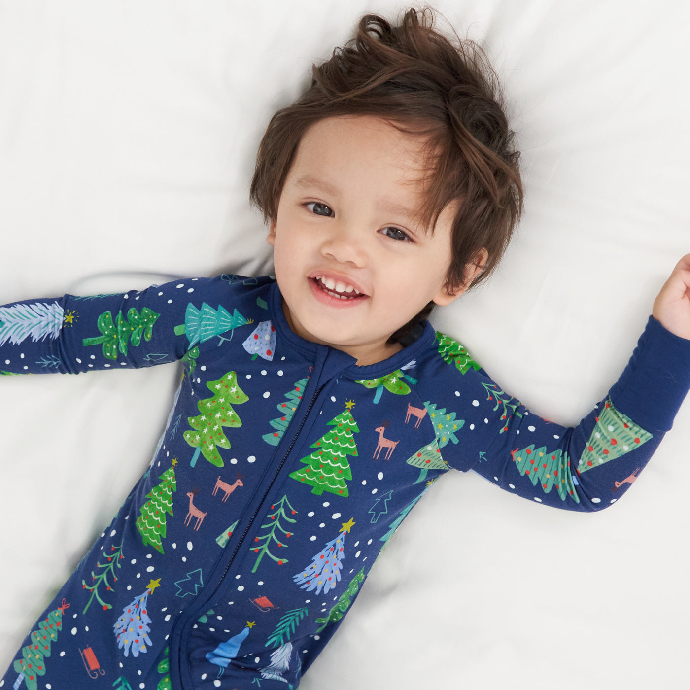 Child laying on a bed wearing a Blue Merry and Bright zippy