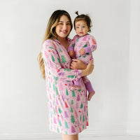 Mother holding her daughter. They are both wearing Pink Merry and Bright pajamas. Mom is wearing Pink Merry and Bright women's long sleeve sleep shirt and child is wearing a matching zippy