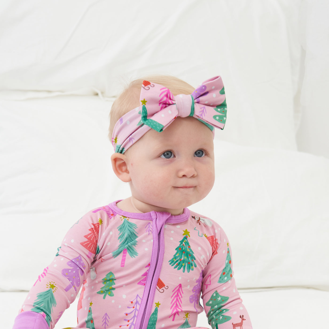 Child wearing a Pink Merry and Bright zippy paired with a matching Pink Merry and Bright luxe bow headband in size newborn to 3T