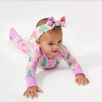 Child crawling wearing a Pink Merry and Bright zippy paired with a matching Pink Merry and Bright luxe bow headband in size newborn to 3T