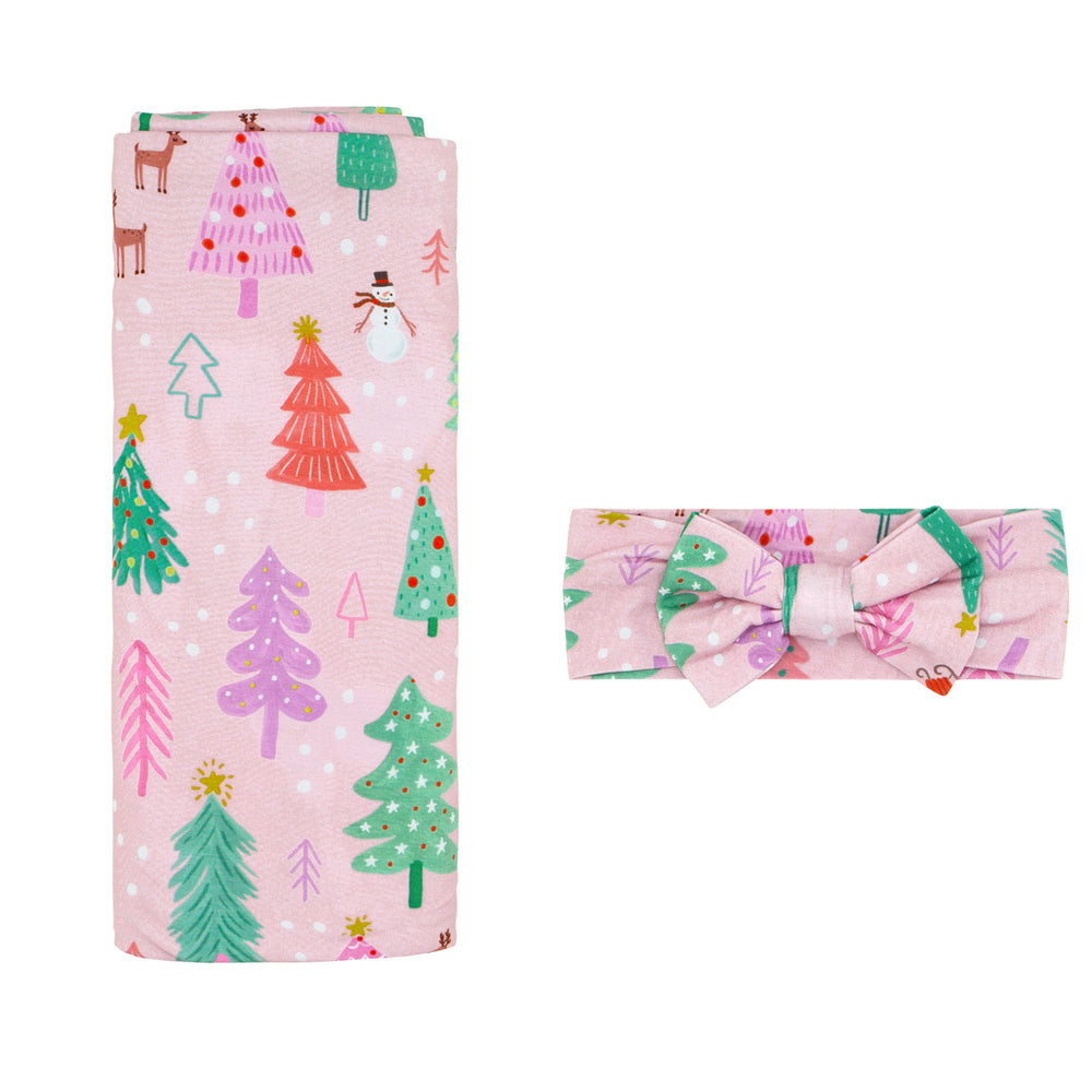 Flat lay image of a Pink Merry and Bright swaddle and luxe bow headband set 