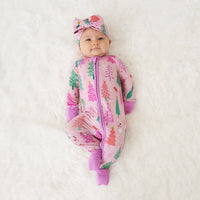 Child laying down wearing a Pink Merry and Bright zippy paired with a matching luxe bow headband
