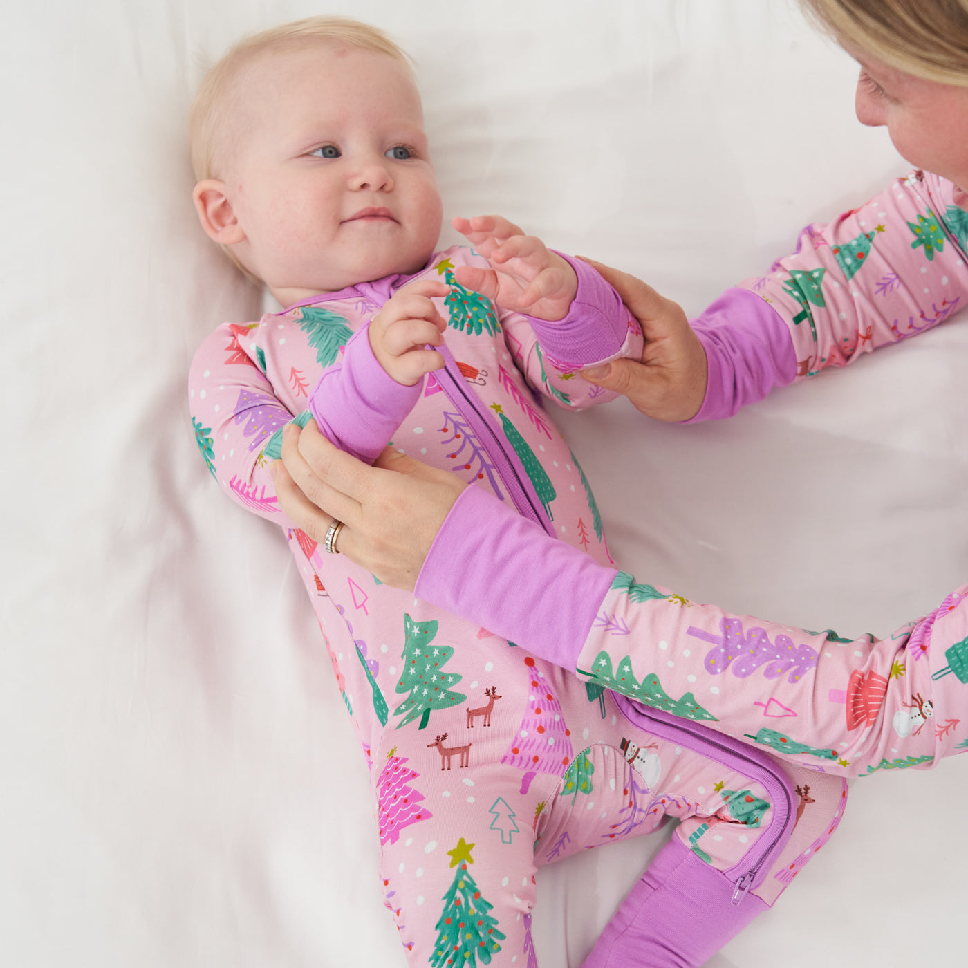 Child laying on a bed wearing a Pink Merry and Bright zippy. Her mom is wearing a matching Pink Merry and Bright women's pajama top
