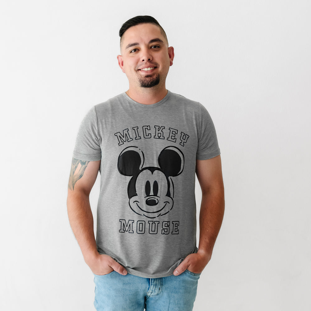 Man with his hands in his pockets wearing a Mickey collegiate men's graphic tee