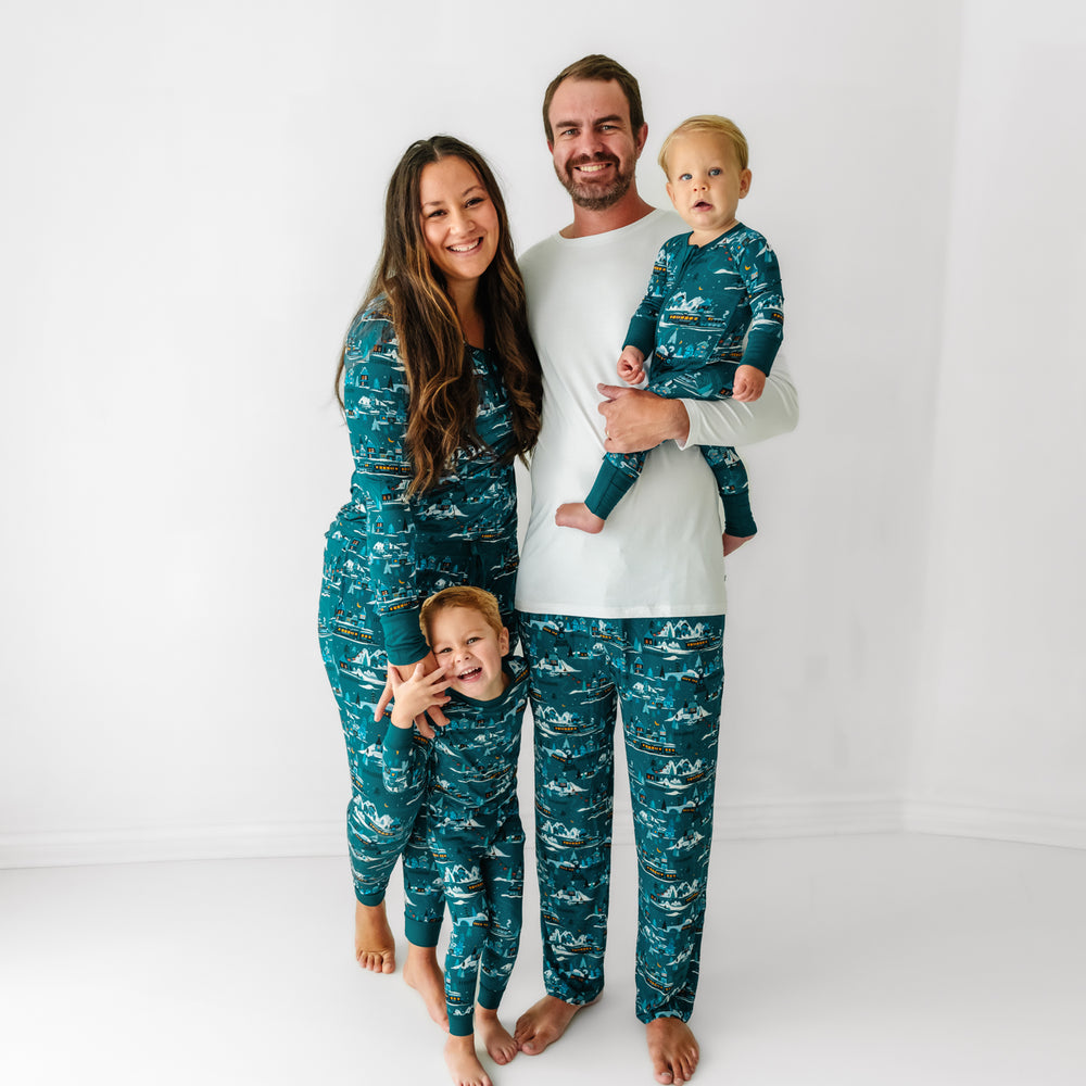 Family of four posing together wearing coordinating Midnight Express pajamas. Dad is wearing Bright White men's pajama top paired with Midnight Express men's pajama pants. Mom is Wearing Midnight Express pajama top paired with matching pajama pants. Children are wearing matching Midnight Express zippy and two piece pajama sets 