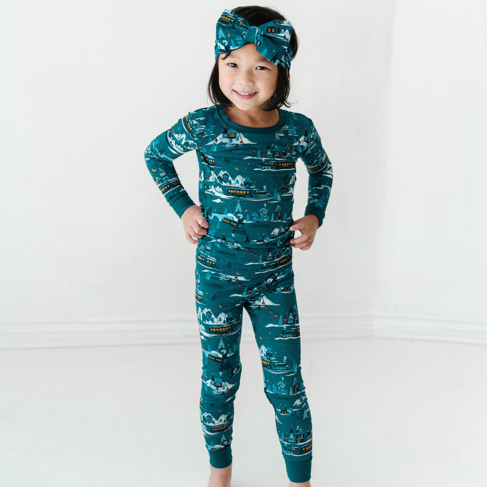 Child wearing a Midnight Express two piece pajama set paired with a matching luxe bow headband