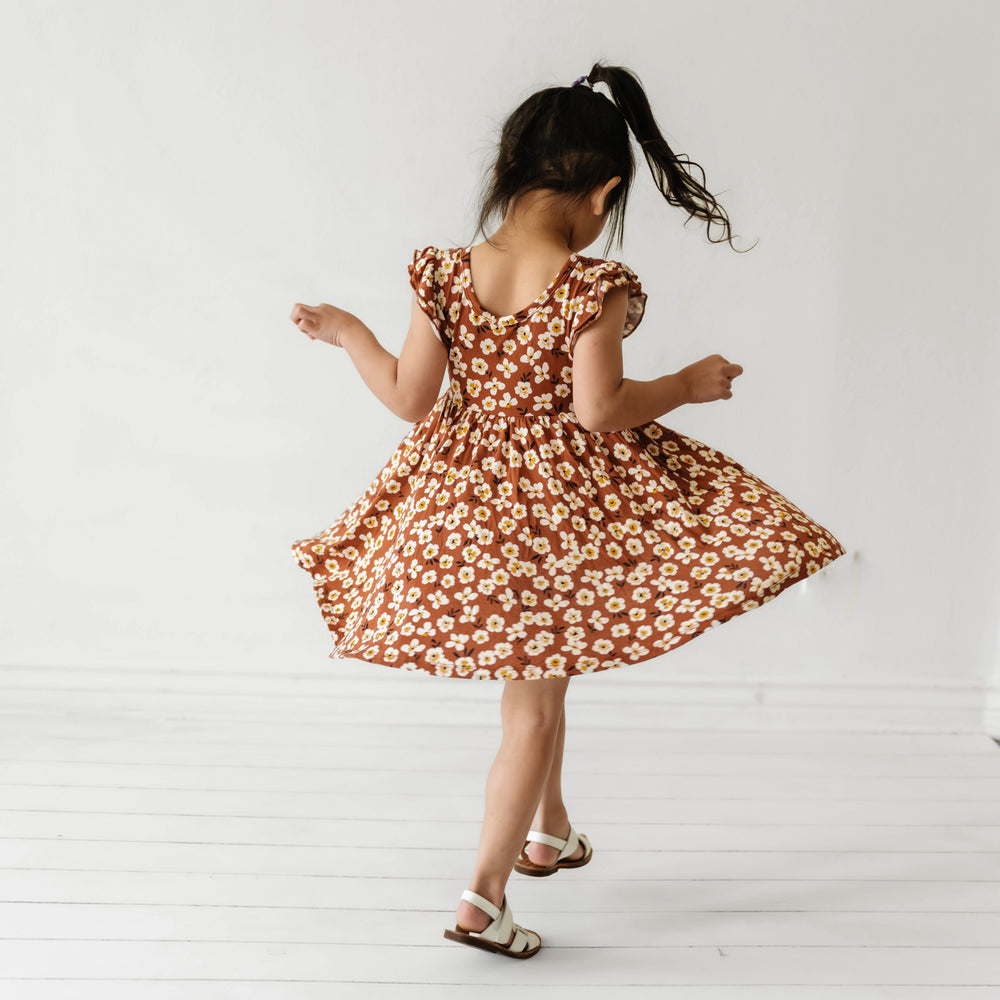 Child spinning around wearing a Mocha Blossom printed twirl dress