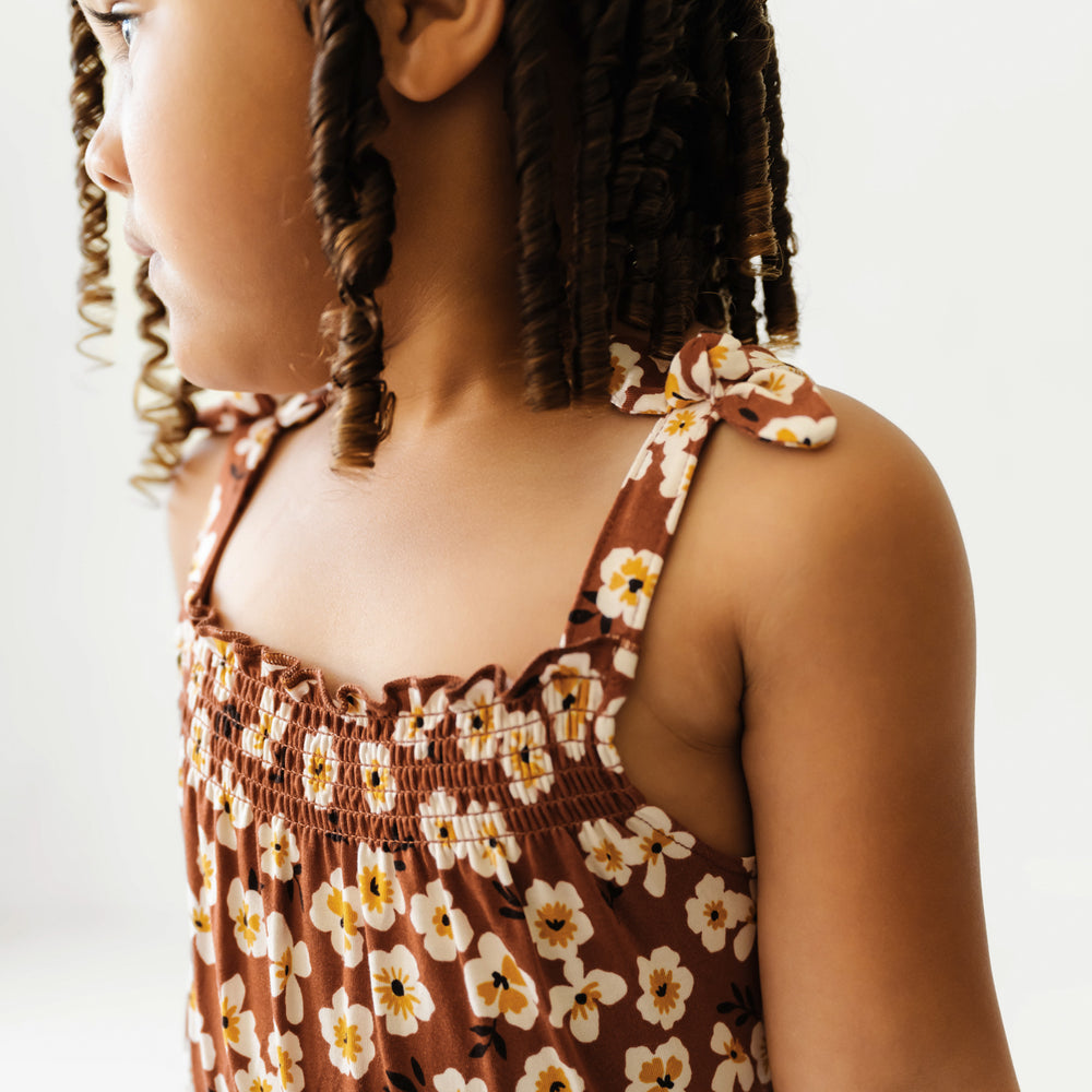 Close up image of a child wearing a Mocha Blossom printed smocked romper